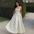 Robe longue à pois écru et noir portée lors d'une journée ensoleillée en bord de mer